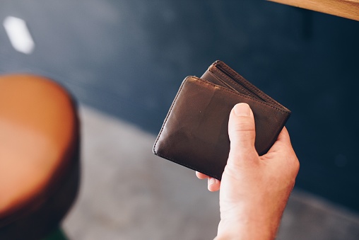 A high angle shot of a male holding his wallet with a blurred background