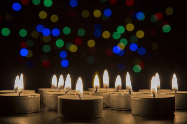 istock Tiny candles igniting together in the dark with lights shining in the background 1440031927