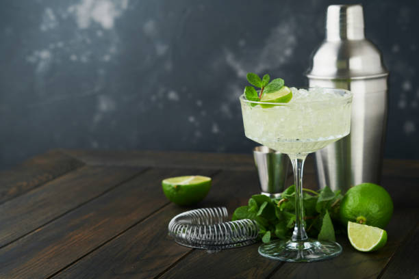 istock Margarita cocktail with lime, tequila, mint and ice on dark table with amazing backlight, copy space. Classic Margarita or Daiquiry Cocktail. Bar card or counter concept. Selective or soft focus. 1440032083