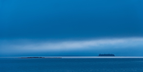 A beautiful shot of the Crow Island in the distance under a cloudy sky at Penobscot Bay
