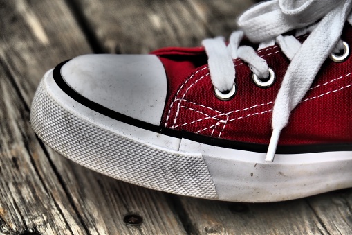 A closeup shot of a red sports shoe with white shoelaces on a wooden surface