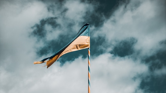 A selective shot of the yellow and blue flag of Ukraine on flagpole on the background of a cloudy sky