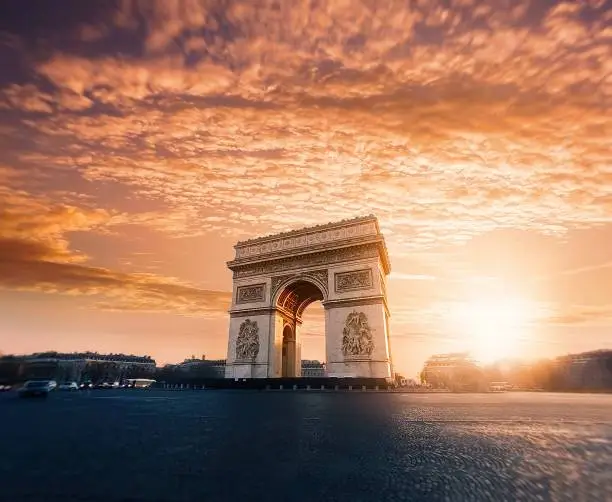 A beautiful low angle shot of Arc de Triomphe or Triumphal Arch in Paris at sunset with amazing sky