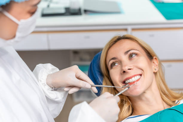 Female dentist examine tooth to Caucasian girl at dental health clinic. Attractive woman patient lying on dental chair get dental treatment from doctor during procedure appointment service in hospital stock photo