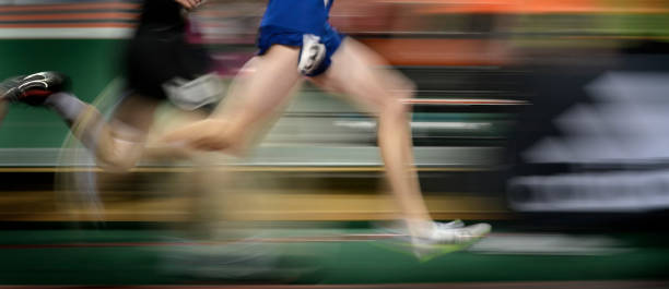 istock Running a Relay Race on Tract Holding Baton 1440034626