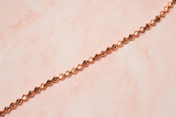 istock Closeup of Copper Beads on a String on a pink background 1440035039