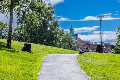 Oslo, Norway – July 05, 2022: A narrow pathway passing through beautiful Torshov Park in Oslo, Norway