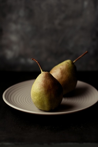 A vertical selective closeup shot of pears on a white plate