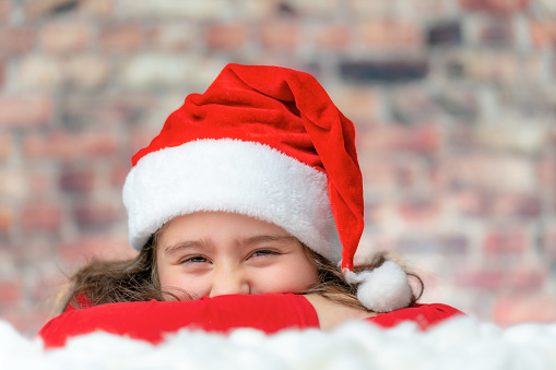 Child in Santa red cloth face close up with a big laugh or smile