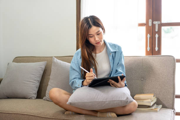 istock Young woman is analyzing strategy goal of business and taking notes on tablet while working on comfortable 1440035938