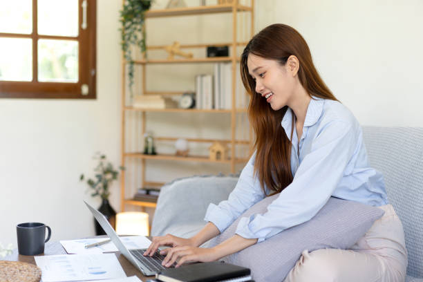 istock Female freelance is reading business data and typing information on laptop while sitting on comfortable 1440036034