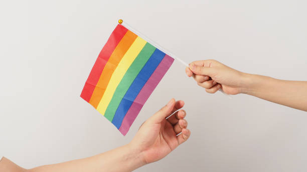 istock Two hands send and receive a rainbow flag on white background. LGBT CONCEPT. 1440036041