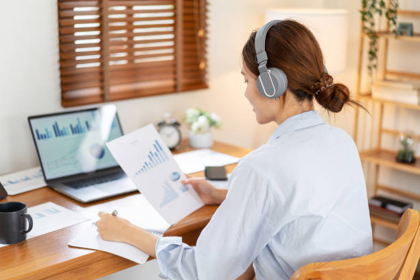 istock Female freelance is reading business data on laptop and document to writing information on notebook 1440036091