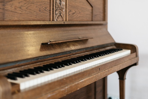 A close shot of an old wooden piano with a blurred background