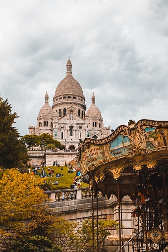 A vertical shot of The Basilica of the Sacred Heart of Paris or Sacre Coeur near a carousel in France