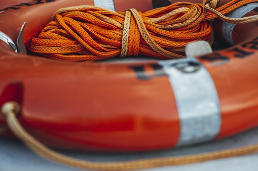 A closeup shot of an orange life ring by a rope on a ship