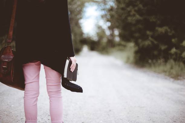 istock a female wearing black jacket and a brown bag holding thick notebook standing on a road 1440037284