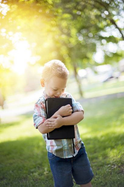 Vertical shot of a child holding the bible against his chest with a blurred background A vertical shot of a child holding the bible against his chest with a blurred background god is love stock pictures, royalty-free photos & images