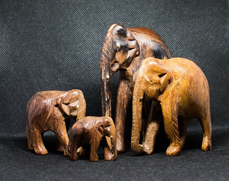 A closeup shot of four brown elephant sculptures with a grey background