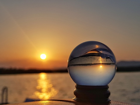 A beautiful shot of the sunset with a reflecting crystal ball up front