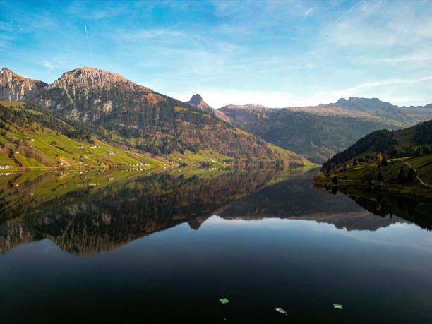 istock Beautiful landscape with Wagitalersee river reflecting forested mountains, sunlit sky background 1440038410