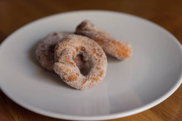 istock 3 handmade spanish christmas icing sugar donuts on a plain white plate on wooden surface - front view - landscape orientation 1440039327