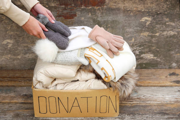 Donation box with winter clothes on an old wooden background.