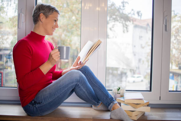 istock Happy woman reading book at home 1440041110