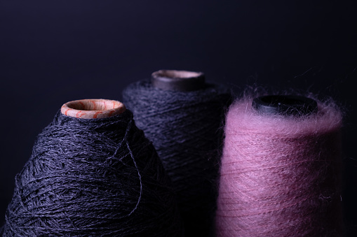 Three bobbins of merino and mohair threads for knitting on a dark background. Skeins of wool for knitting