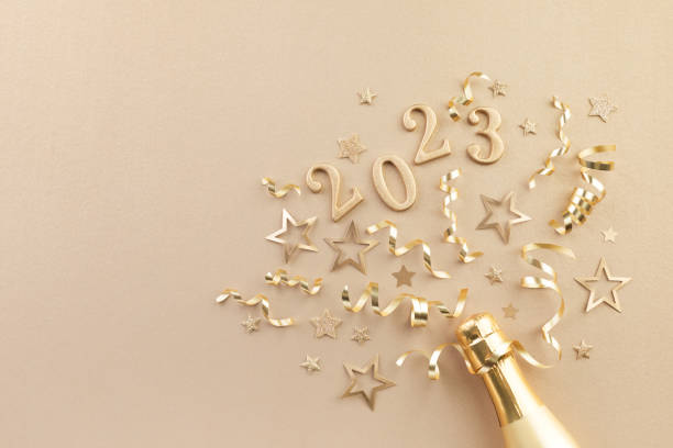 Christmas and New Year background with golden champagne bottle, party decorations, confetti stars and 2023 numbers. stock photo