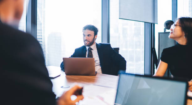 Successful male and female partners have briefing collaboration on business project using modern laptop devices for analyzing information during brainstorming in conference room, group of experts