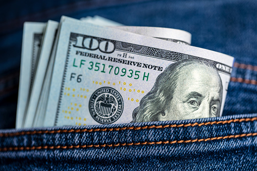 The man pulls a brown leather wallet out of his jeans pocket