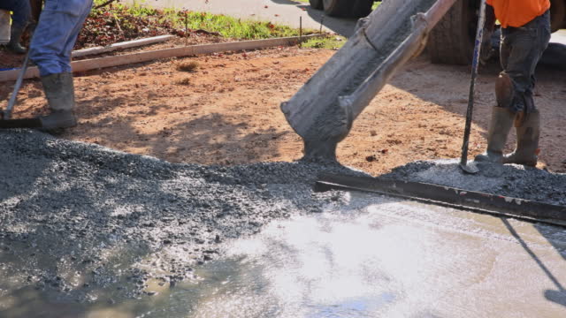 Work on pouring wet concrete while paving the driveway by concrete construction contractors