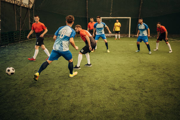 Male soccer match Group of men, male soccer players playing a match on soccer field indoors. soccer team captain stock pictures, royalty-free photos & images