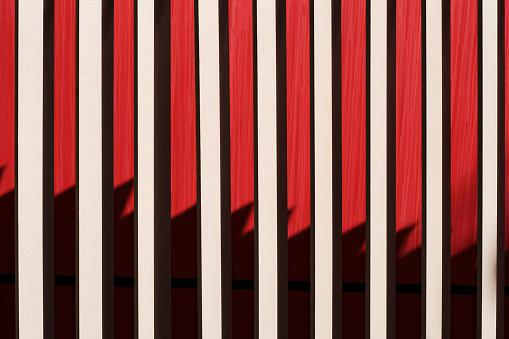 abstract detail of a metal grey fence with a red background