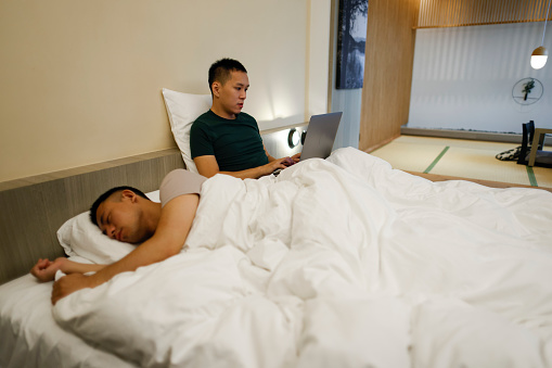 Two men working on laptop in hotel room during travel vacation