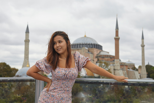 long haired brunette traveler in pink dress posing happy at sultanahmet square, istanbul