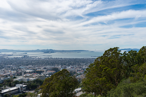 View looking west across Berkeley, Oakland and the San Francisco Bay towards a foggy Golden Gate Bridge and city of San Francisco, California on a cloudy day.