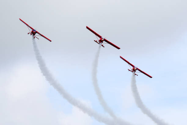 tre aerei sportivi rossi fanno un volo parallelo durante uno spettacolo aereo - flying air vehicle performance airshow foto e immagini stock