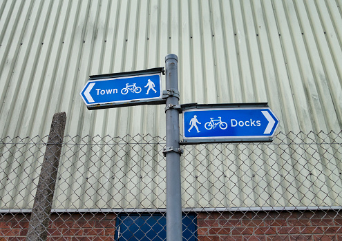 Two blue signs giving directions for walk or cycling to the Town and to the Docks in King’s Lynn, Norfolk, Eastern England.
