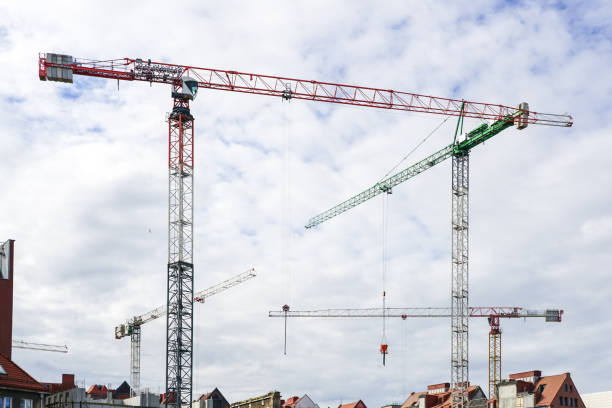 istock Several construction tower cranes at city construction sites against a cloudy sky background 1440061204