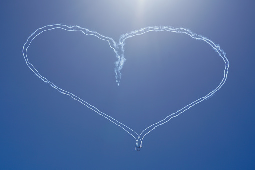 Two gliders with smoke trails soaring formed a beautiful big heart shape in the blue sky