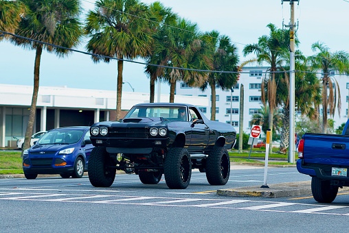 Titusville, Florida, USA - May 29, 2020: The driver of a 1970s era Chevrolet El Camino with a raised suspension and oversized tires waits to proceed at an intersection in downtown Titusville.