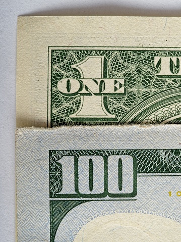 One to one hundred, a comparison of American paper currency.  Macro image of two paper currency bills showing the different writing on the one dollar and one hundred dollar bills.