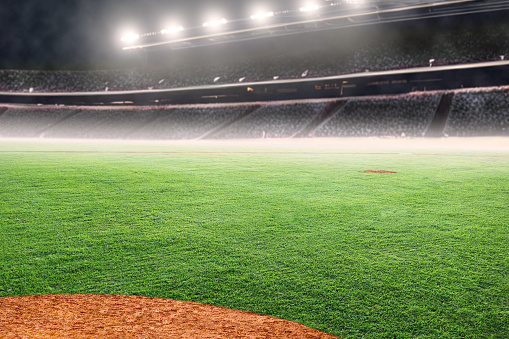 Baseball diamond on field at brightly lit outdoor stadium. Focus on foreground and shallow depth of field on background and copy space.