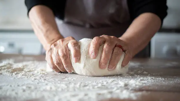 Close-up elderly woman making pizza dough