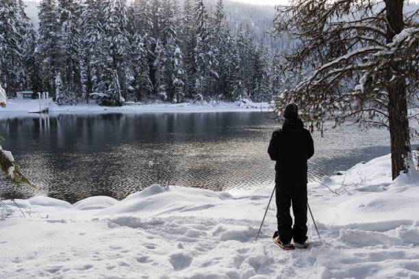 istock Man Looking at View Across Lake While Snowshoeing 1440071636