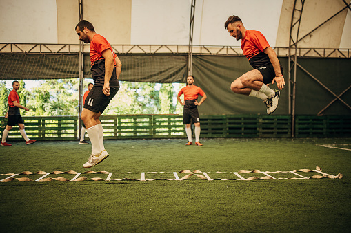 Group of men, male soccer players training on soccer field indoors.