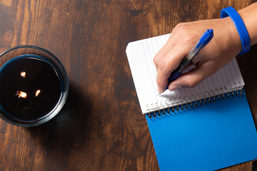 Overhead shot of a hand writing in a blue notebook