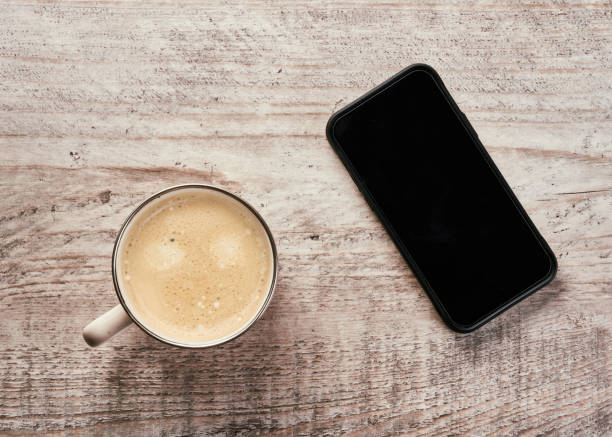 istock Wooden table with a smartphone, a keyboard, a cup of coffee and a notebook. 1440078631
